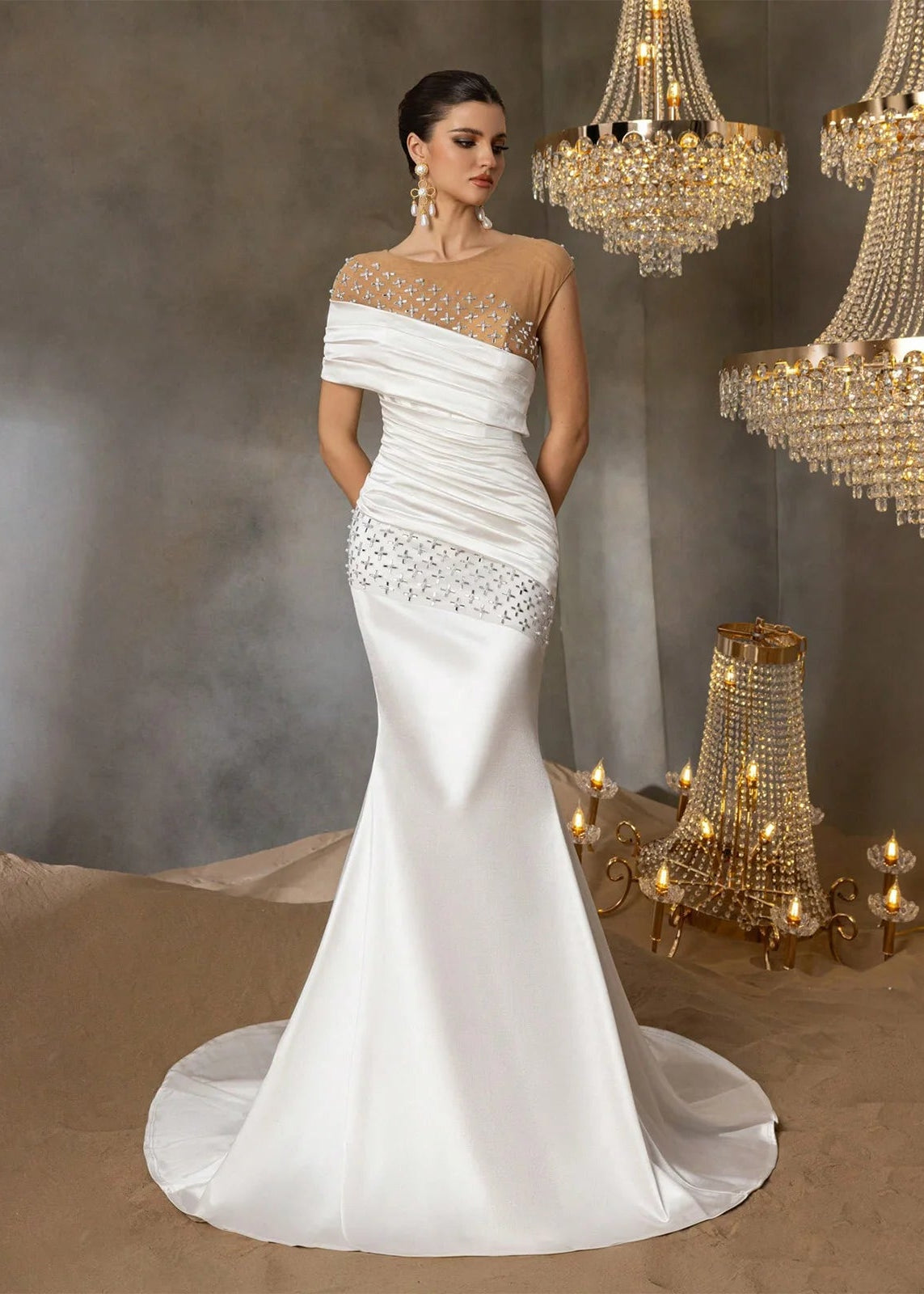 White wedding dress with intricate detailing in a decorated room with chandeliers.